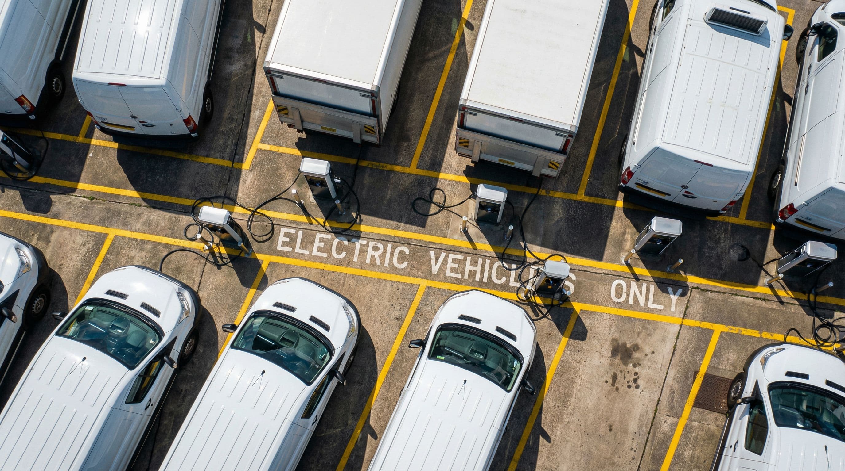 Electric commercial vehicles charge simultaneously at UK fleet depot facility.