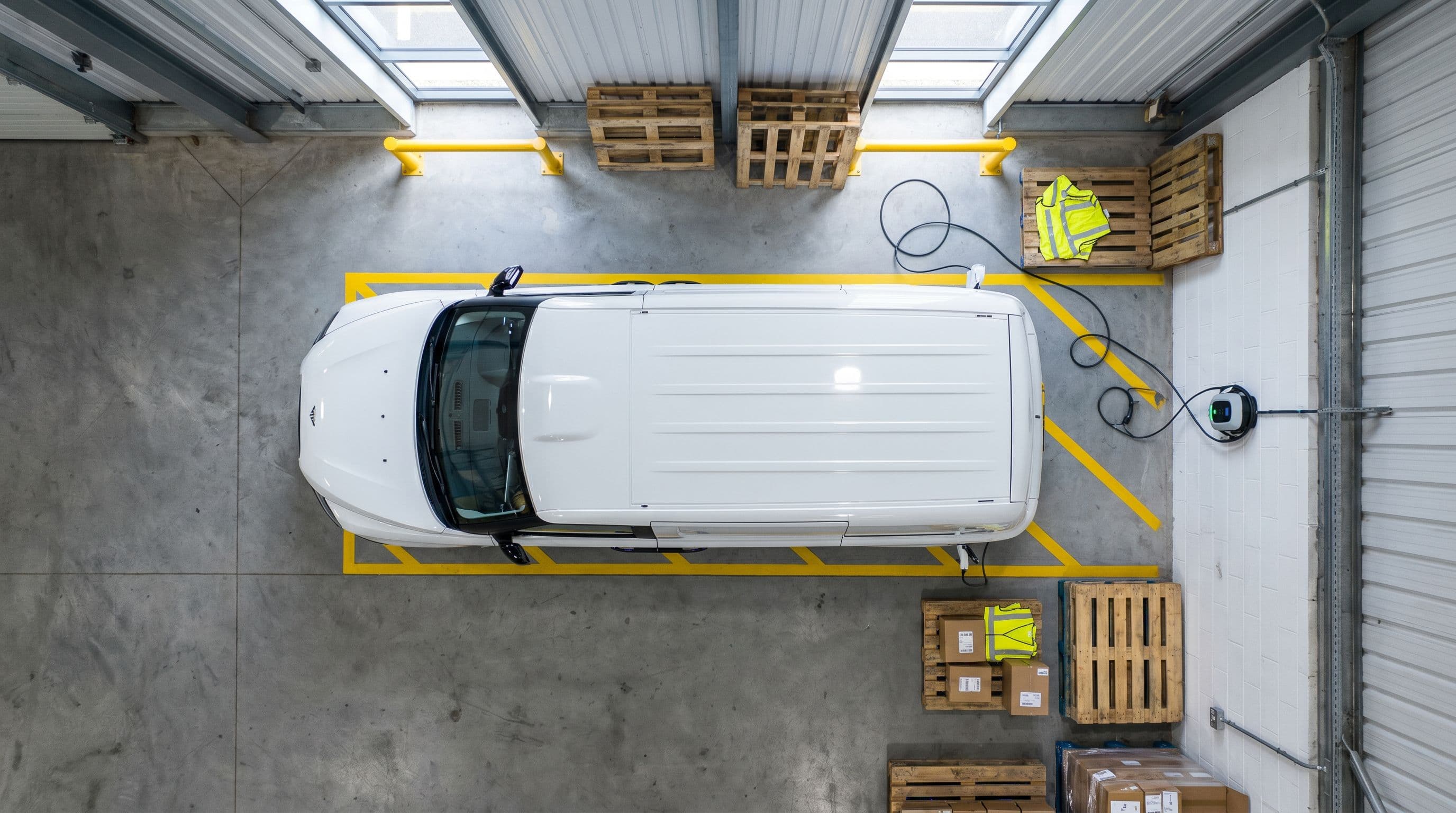 Electric delivery van charges at UK logistics depot loading bay