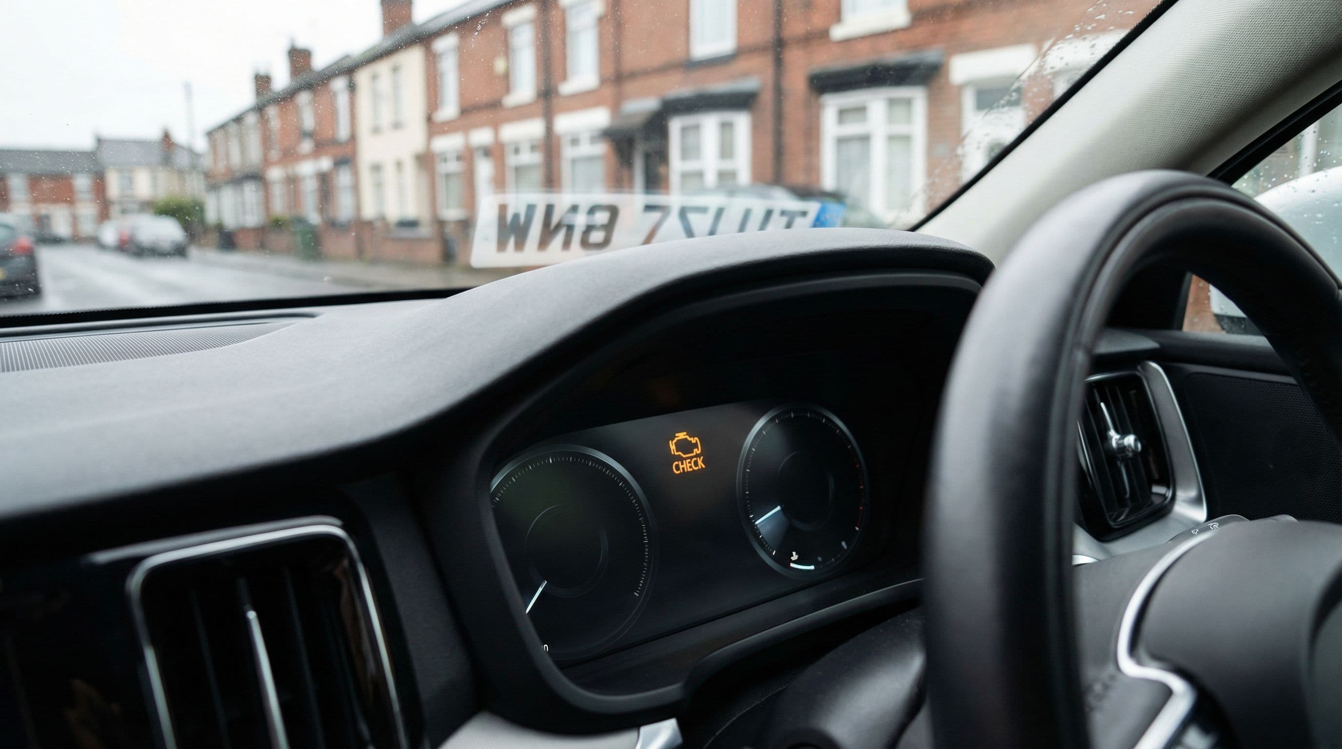 An illuminated engine warning light glows on a car's dashboard display.