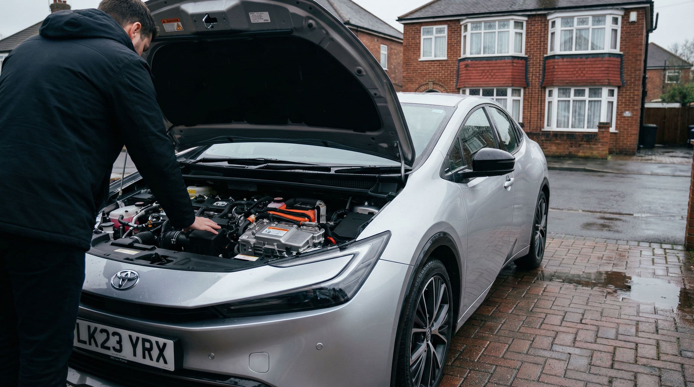 Owner inspects hybrid engine components under the bonnet of their car