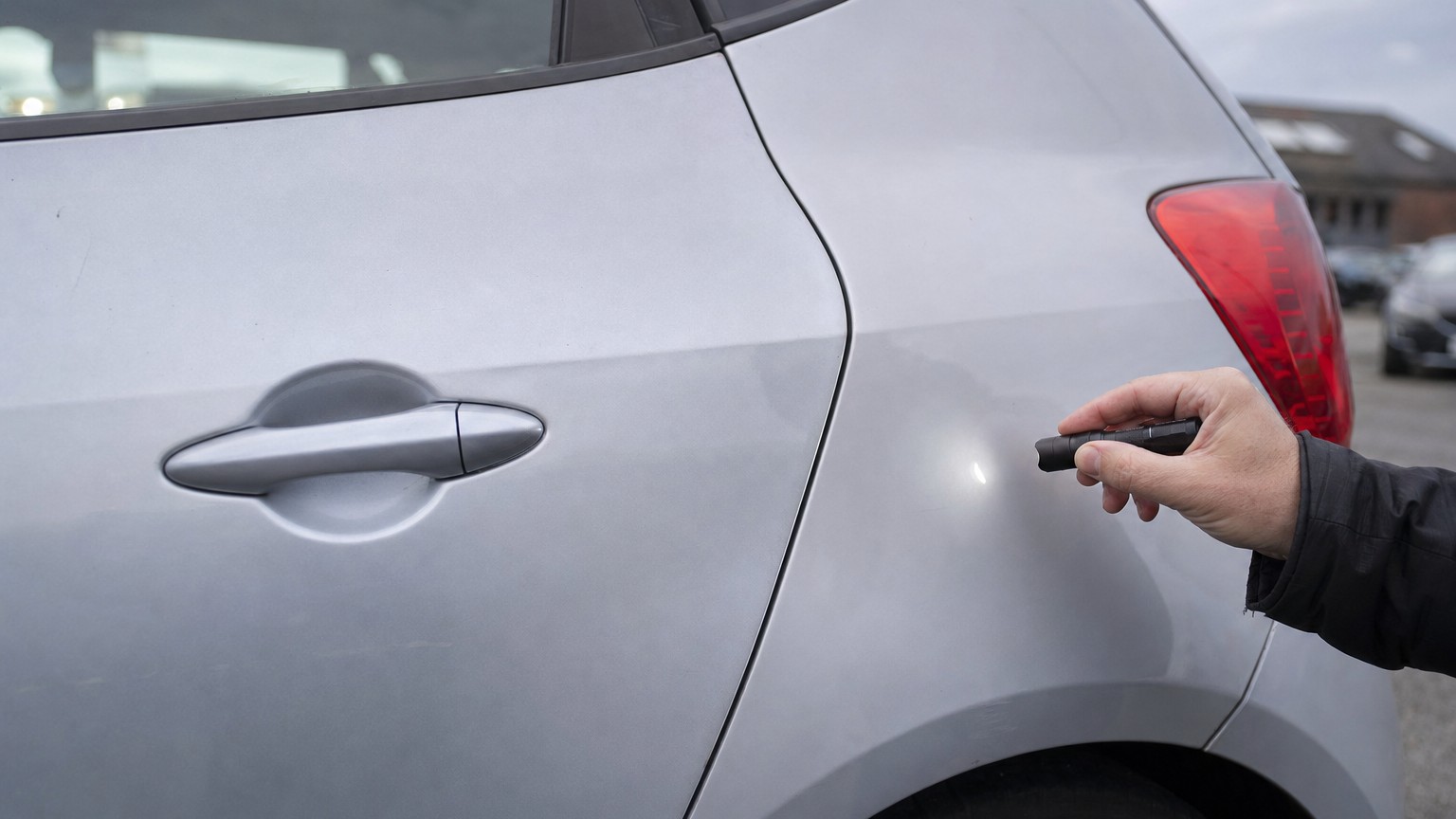 The resprayed rear door of a used hatchback, a shade off the panel beside it, with an uneven panel gap
